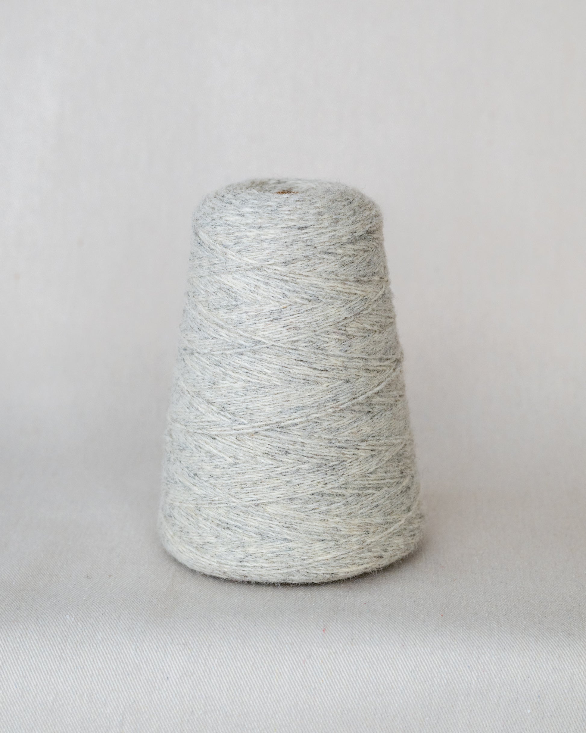 Spool of gray yarn on a light gray background