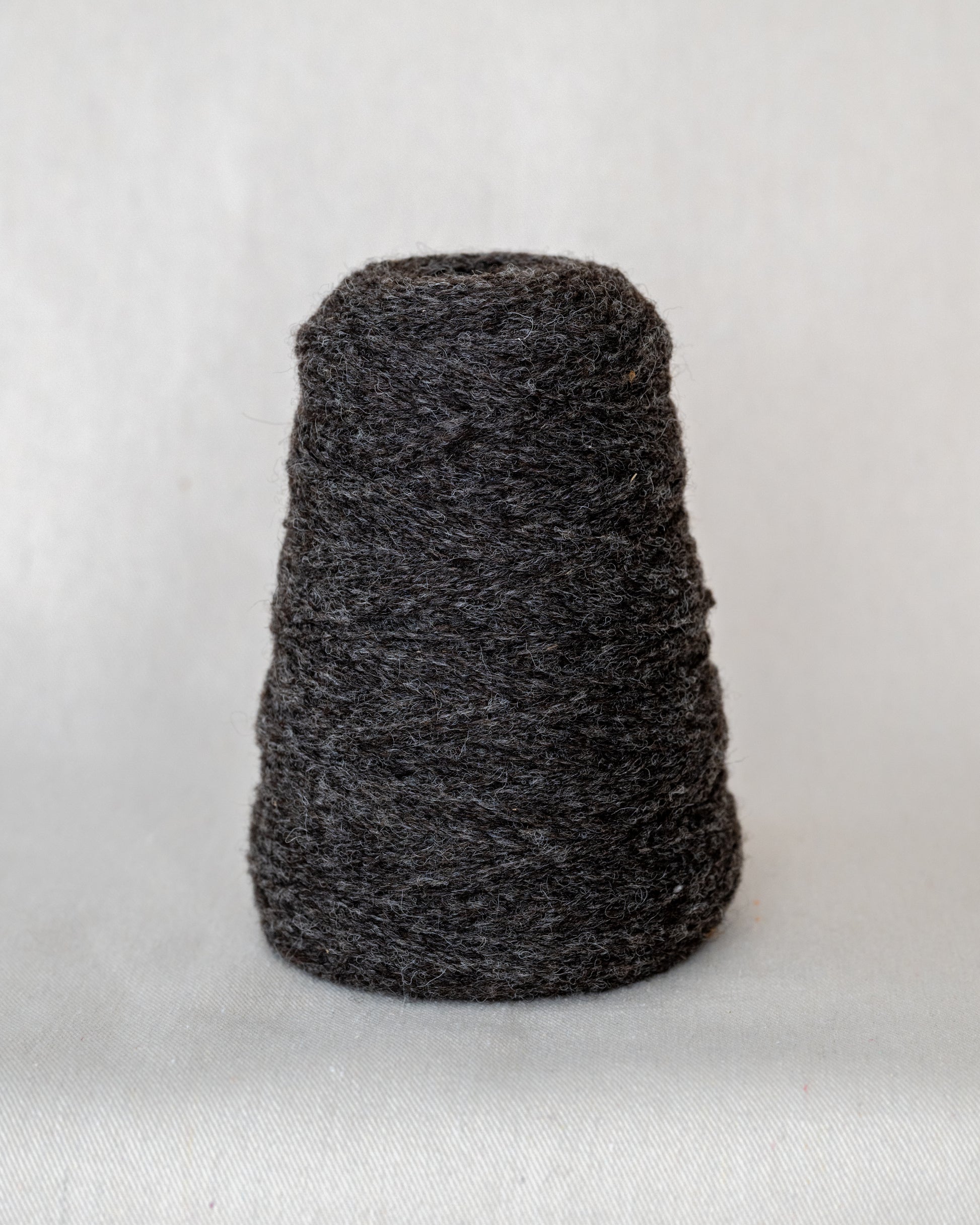 Dark gray skein of yarn on a light gray background